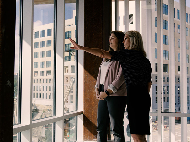 Two women pointing out a window